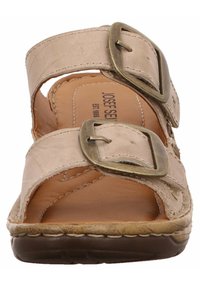 Beige lederen sandaal met twee verstelbare banden en grote bronzen gespen. Zachte, gevoerde binnenzool en gestructureerde rubberen buitenzool.