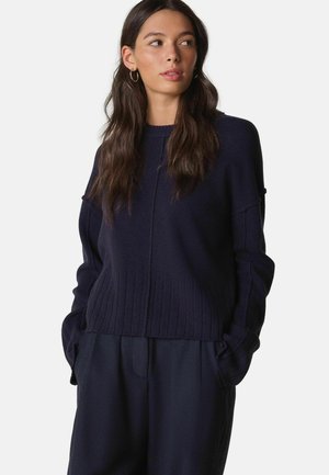 Navy blue knitted sweater with ribbed hem and dropped shoulder design. Soft texture, featuring a clean silhouette and round neckline.