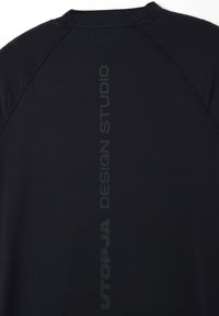 Camisa atlética negra con una textura suave, mangas cortas y un logo vertical "UTOPJA DESIGN STUDIO" en un acabado contrastante.