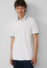 Witte polo shirt van katoen, met een marineblauwe contrastkraag en mouwranden, voorzien van een subtiele geborduurde logo op de borst.
