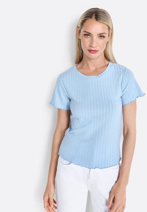 Lichtblauw geribbeld topje met korte mouwen, voorzien van een gegolfde halslijn en zoom, gemaakt van een textuurstof, gecombineerd met witte broek.