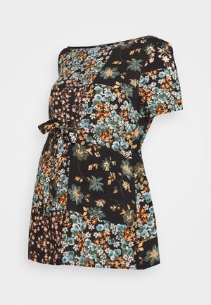 Top floral negro con mangas cortas, que presenta un patchwork de patrones florales coloridos en azul, verde, naranja y crema. Incluye un detalle de lazo.