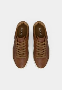 Baskets en cuir marron à bouts ronds, avec des accents beige contrastants et des lacets beiges. Présentent un design cousu et une semelle extérieure en caoutchouc blanc.