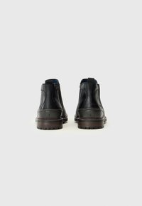 Bottines en cuir noir avec une finition texturée, des panneaux latéraux élastiques et une semelle superposée marron. Possède des tirants à l'arrière pour un enfilage facile.