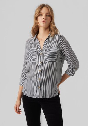 Chemise à rayures noire et blanche, dotée de deux poches poitrine, de manches retroussées et d'une coupe décontractée. Fabriquée en tissu léger.