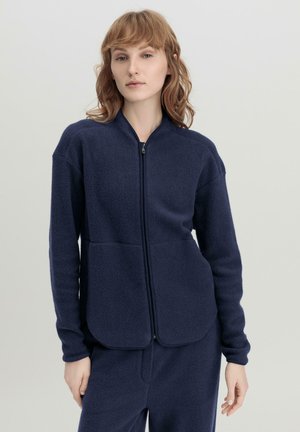 Marine fleece jack met voorrits, hoge kraag, twee grote zakken en lange mouwen. Zachte textuur en losse pasvorm.