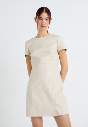 Abito in finta pelle beige a maniche corte con silhouette aderente, dettagli di cucitura e scollatura rotonda. Tessuto liscio e lunghezza a metà coscia.