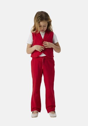 Rode vest met revers over een wit T-shirt, gecombineerd met losse rode broek. De outfit heeft een gestructureerde stof en een elastische tailleband.