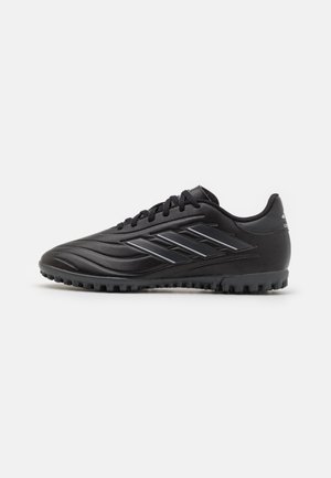 Botas de fútbol sintéticas negras con una textura suave, que presentan rayas negras prominentes en el lateral y una suela de goma texturizada para mayor tracción.