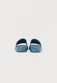 Infradito in plastica blu con apertura sul retro, punta arrotondata e suola texturizzata per una migliore presa, caratterizzati da una finitura liscia e un design minimalista.