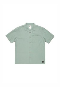 Short-sleeve button-up shirt in light green textured fabric, featuring a chest pocket and brown buttons. Logo patch at the bottom left.