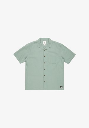 Koszula z krótkim rękawem zapinana na guziki w jasnym zielonym, teksturowanym materiale, z kieszonką na piersi i brązowymi guzikami. Naszywka z logo na dolnym lewym rogu.