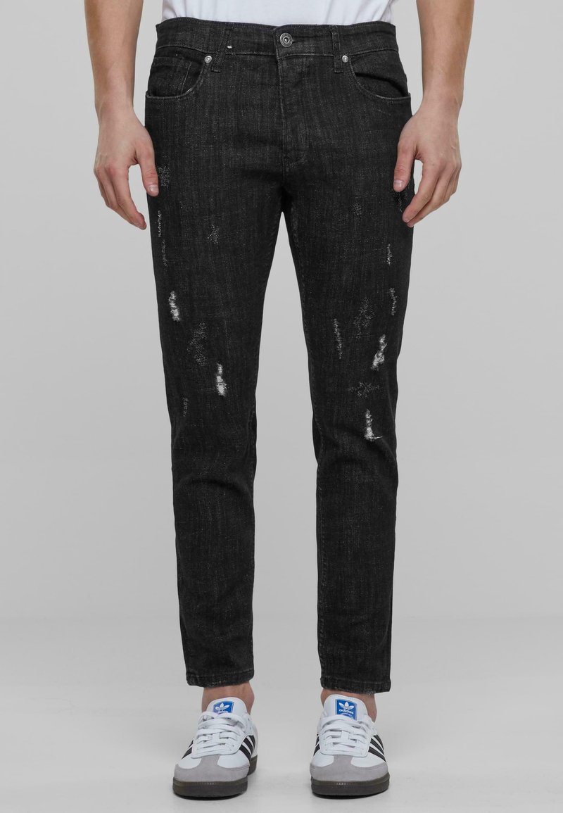 Mustat farkut slim-fit-mallissa, joissa on kuluneita alueita ja kevyttä haalistumista. Varustettu viidellä taskulla ja nappikiinnityksellä.