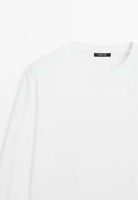 T-shirt à manches longues blanc avec col côtelé visible et étiquette noire portant la mention "Massimo Dutti Made in Portugal" sur fond blanc.