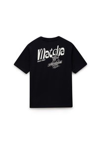 Sort T-shirt med hvidt grafisk tekst "Matcha Since 1987" og tegneseriefigur af matcha-drik med et skilt, der siger "Ambassador" på bagsiden.