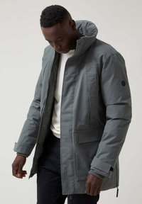 Chaqueta gris con cremallera, cuello alto, grandes bolsillos frontales y puños elásticos. Fabricada con un material duradero y con una textura suave.