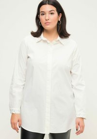 Hvid langærmet skjorte med knap-ned krave, udstyret med hævede manchetter og lige snit, lavet af let bomuldsstof.