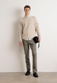 Beige sweatshirt, lyse grå bukser, sort skuldertaske, sorte sko. Glat tekstur, enkelt design, minimale accenter, velegnet til hverdagstøj.