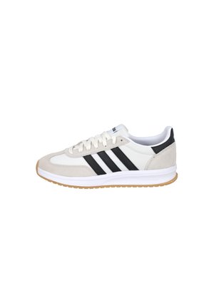 Zapatilla blanca y beige con franjas negras, cierre de cordones y suela de goma, vista de lado sobre fondo blanco.