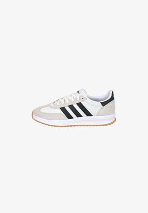 Zapatilla blanca y beige con franjas negras, cierre de cordones y suela de goma, vista de lado sobre fondo blanco.