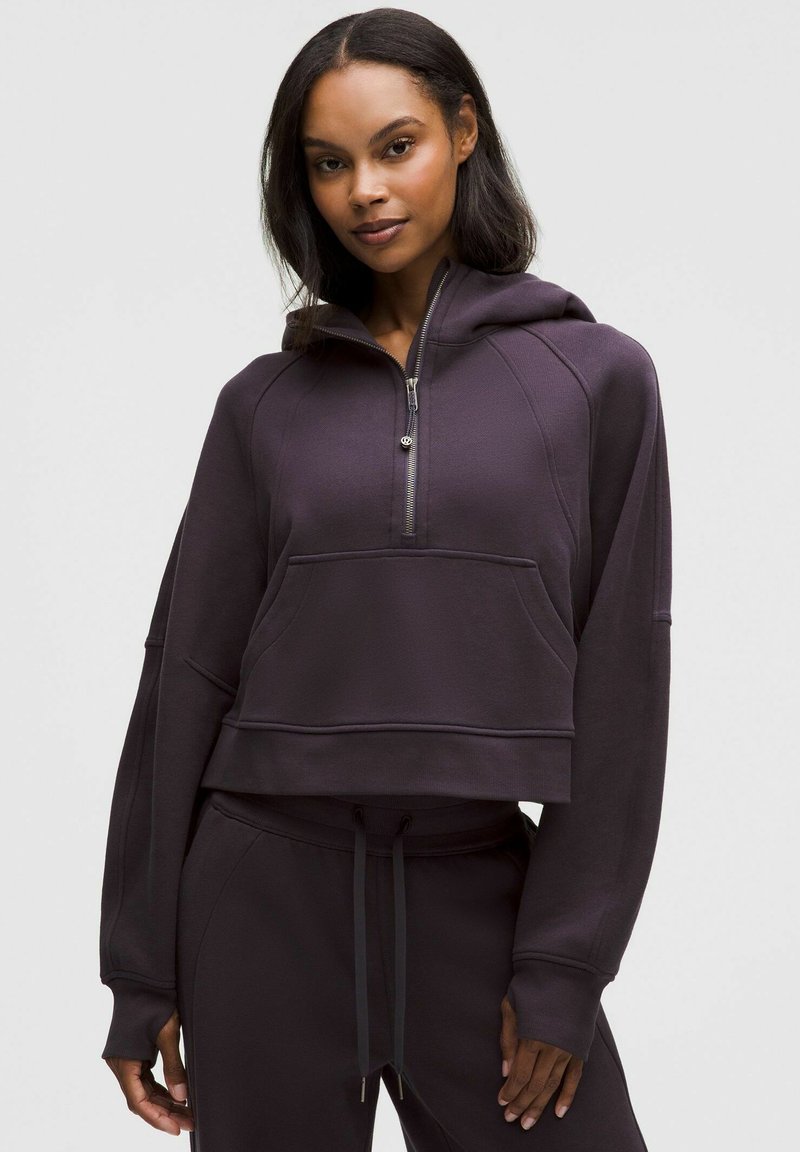 Lila gekürzter Hoodie mit Reißverschluss am Kragen, gerippten Bündchen und Fronttasche. Der Stoff wirkt weich und strukturiert, geeignet für den Freizeitgebrauch.