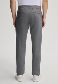 Pantaloni grigi a fantasia realizzati in un tessuto con una sottile texture, dotati di tasche posteriori e abbinati a sneakers bianche.