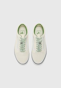 Crème canvas sneakers met groen en witte geruite veters, witte zijstripes en een gevoerde groene kraag, met een zwarte rubberen zool.
