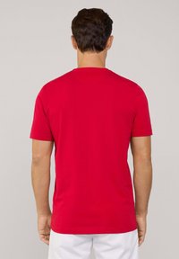 Camiseta roja de manga corta con cuello redondo, hecha de una tela suave. Presenta una parte posterior lisa sin logotipos ni patrones visibles.
