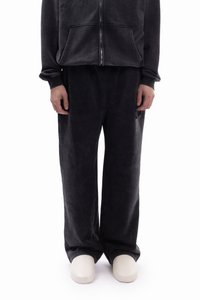 Ciemnoszara bluza z kapturem z zamkiem błyskawicznym i przednimi kieszeniami, zestawiona z szerokimi spodniami o dopasowanym kolorze. Miękka, teksturowana tkanina, minimalistyczny design i neutralny kolor.