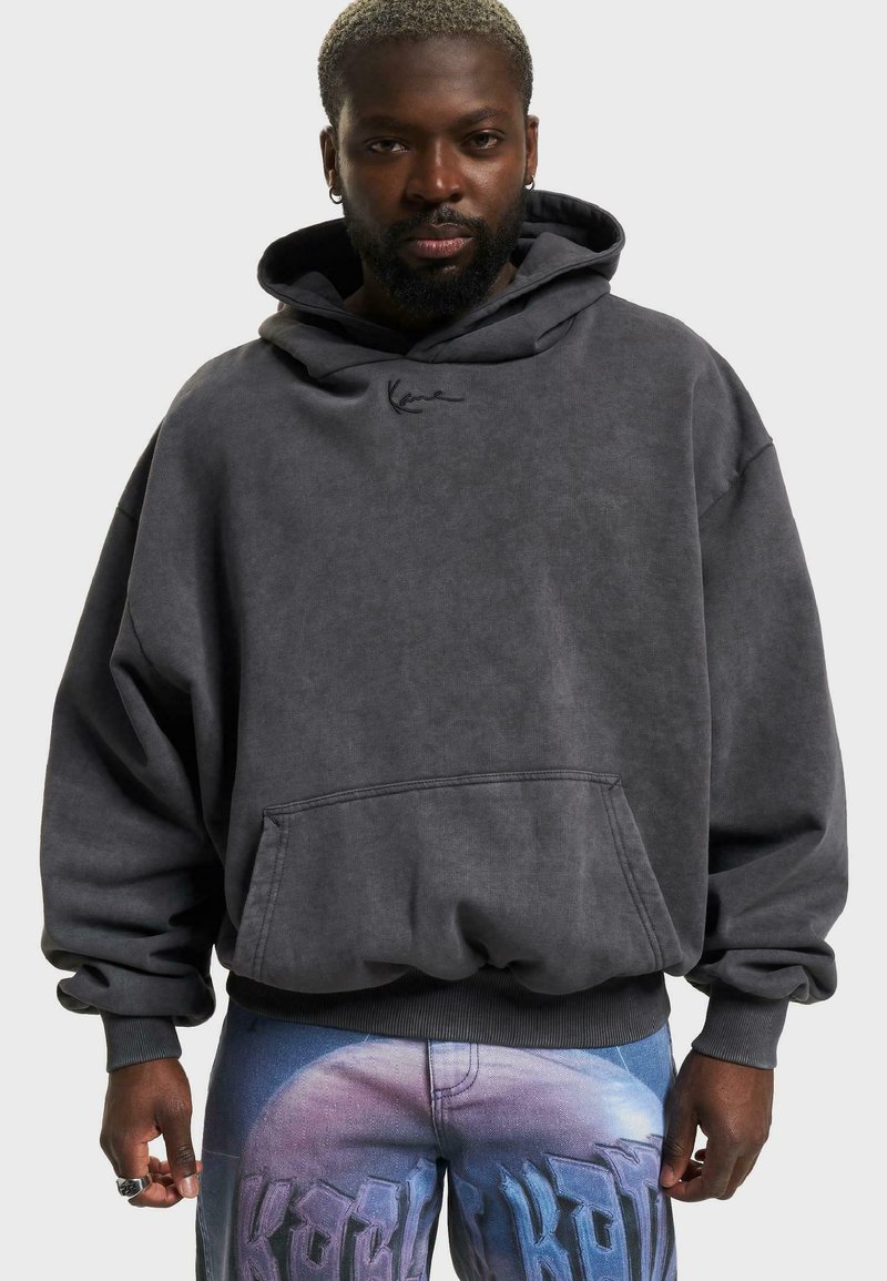 Mørkegrå oversized hoodie med en kengurulomme, prydet med et diskret logo. Glat stof med en afslappet pasform, suppleret med ribbede cuffs.