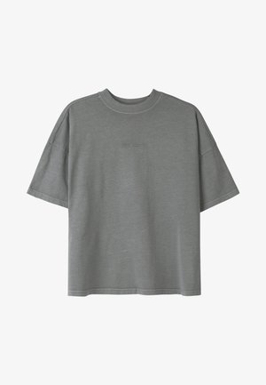 T-shirt oversize gris en coton doux, avec un col rond, des manches courtes et un logo subtil en relief sur le devant.