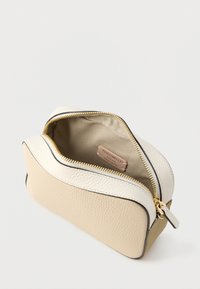 Tan and cream zip pouch made of textured leather. Features gold hardware and a soft fabric interior with a brand tag visible inside.