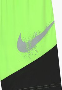 Neongrön och svart tygavsnitt med en silverfärgad Nike-swoosh-logotyp och en splatterdesign.