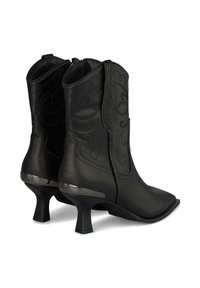 Botas de tobillo de imitación cuero negro con patrones florales bordados, puntera puntiaguda y un pequeño tacón de ciervo. Acento plateado en la suela del tacón.