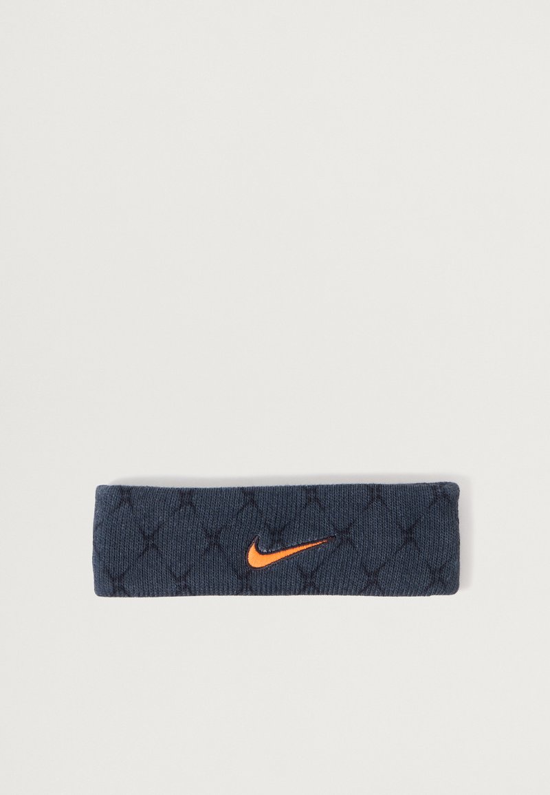Námořnická látková čelenka s prošívanou texturou, s oranžovým logem Nike swoosh. Má elastický, přiléhavý design pro pohodlí.