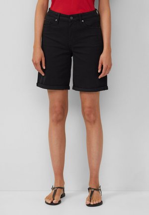 Shorts en denim noir avec un ourlet roulé, cinq poches et une fermeture à bouton à l'avant. Associés avec un haut rouge et des tongs noires.