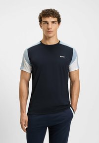 Marinblå kortärmad T-shirt med ljusblå och vita accenter på axlarna. Har rund hals och en liten vit "BOSS"-logotyp på bröstet.