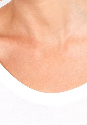 Haut blanc à encolure dégagée en coton lisse, dévoilant une partie de la peau ; texture minimale et design sans coutures soulignent la simplicité.