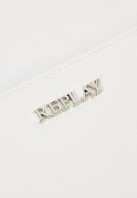 White leather wallet featuring embossed silver metal lettering spelling "REPLAY." Smooth texture with stitching along the edges.