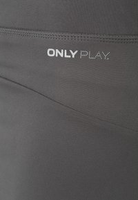 Leggings deportivos negros con una textura suave, que presentan un diseño de costura sutil y un logo impreso "ONLY PLAY" en blanco.