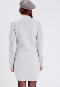 Vestido de suéter de punto gris claro con mangas acanaladas y un escote redondo, que presenta una silueta ajustada y una textura suave.