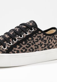 Plátěné tenisky s béžovým a černým leopardím potiskem, s černými šněrovadly, stříbrnými očky a bílou gumovou podrážkou.