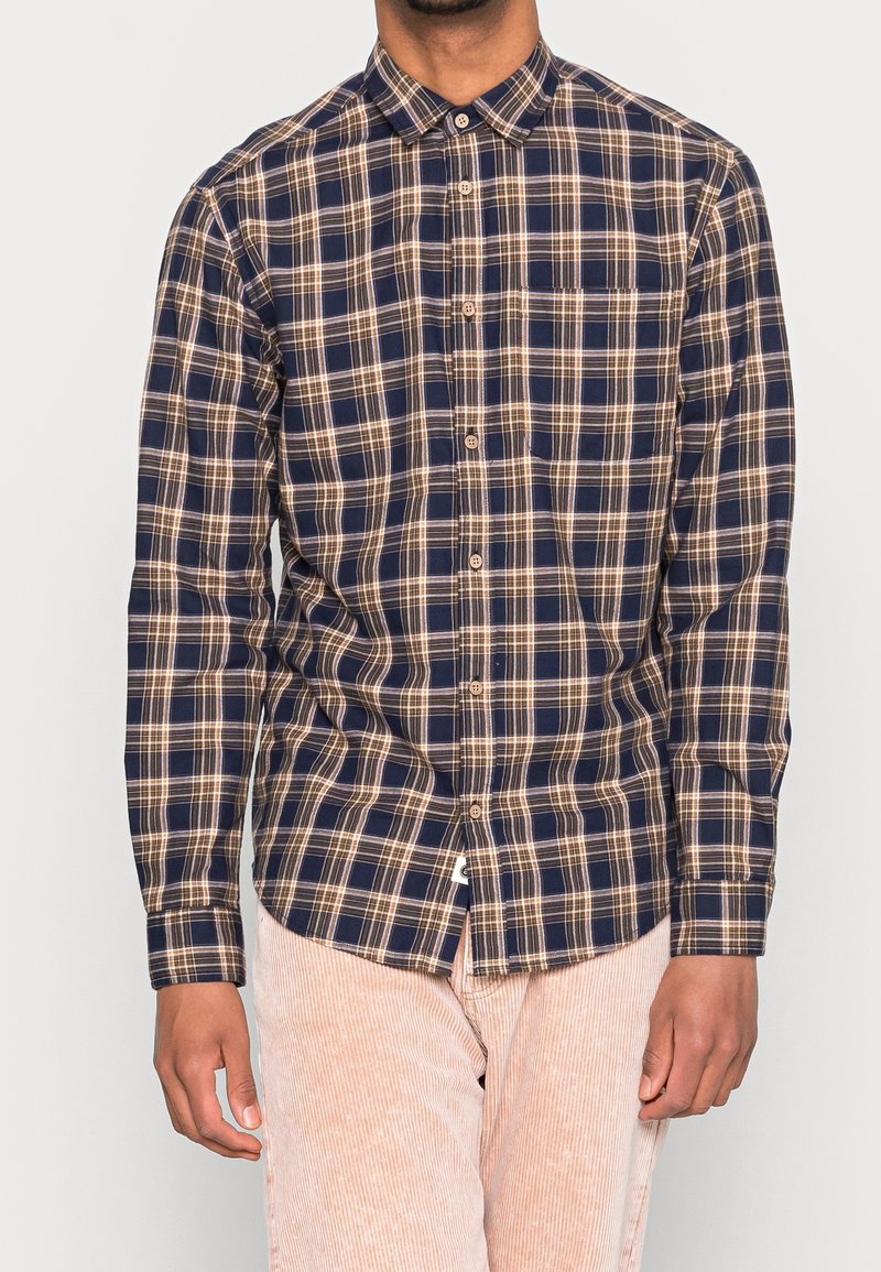 Camisa de manga larga a cuadros en azul marino y beige con cuello abotonado, un bolsillo en el pecho y dobladillo curvado, hecha de tela a cuadros.