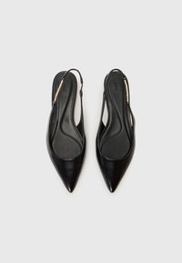 Sapatos slingback pretos de couro com bico fino e forro suave, apresentando uma fita fina e um detalhe simples em metal dourado.