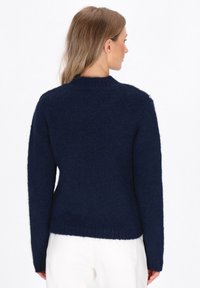 Maglione lavorato a maglia blu navy con colletto a costine, maniche lunghe e bottoni decorativi sulla spalla. Texture morbida e design aderente.
