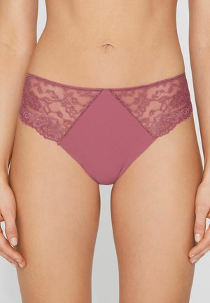 Mujer con ropa interior estilo bikini en encaje malva y tela sólida, mostrada desde la cintura hasta la mitad del muslo, con las manos relajadas a los lados.