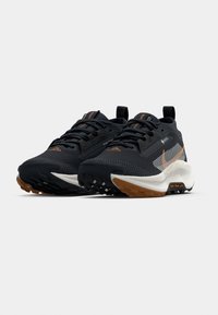 Schwarze Laufschuhe mit einer strukturierten Oberseite, orangefarbenen Akzenten, reflektierenden Details und einer robusten Sohle. Verfügen über eine gedämpfte Mittelsohle für zusätzliche Unterstützung.