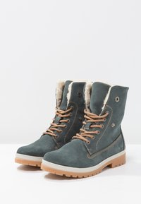 Bottines en daim gris avec lacets couleur camel, doublure en fausse fourrure, couture latérale, et semelles en caoutchouc dotées d'une semelle texturée pour une meilleure adhérence.