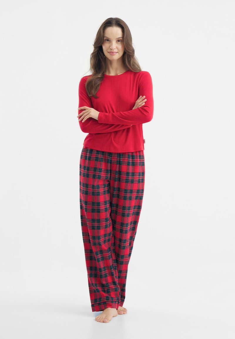 Haut rouge à manches longues associé à un pantalon de pyjama à carreaux aux couleurs rouge, noir et vert. Tissu doux avec une coupe décontractée et une jambe large.