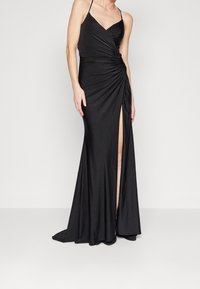 Černé večerní šaty s přiléhavým korzetem, řasenou texturou a rozparkem až do stehna. Obsahují tenké ramínka a jsou dlouhé až na zem.